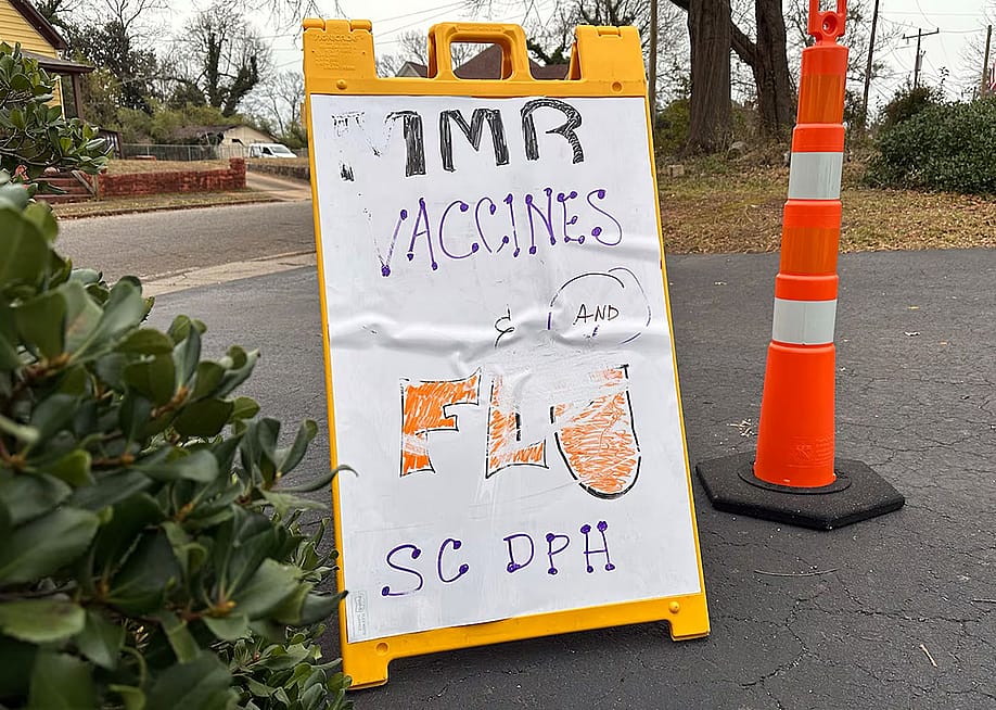 A sign advertising MMR and flu vaccines in a parking lot next to an orange pylon in South Carolina where outbreak response leaders have been trying to encourage the public to get vaccinated during a measles outbreak. — Alison Young // Healthbeat