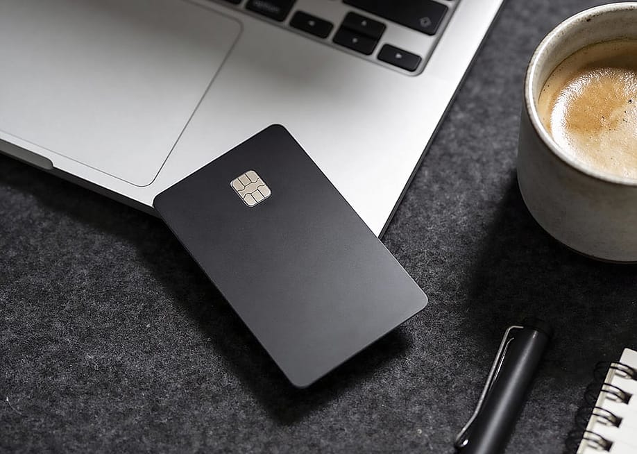 A black credit card on the edge of a laptop. — Ramadanovic // Shutterstock