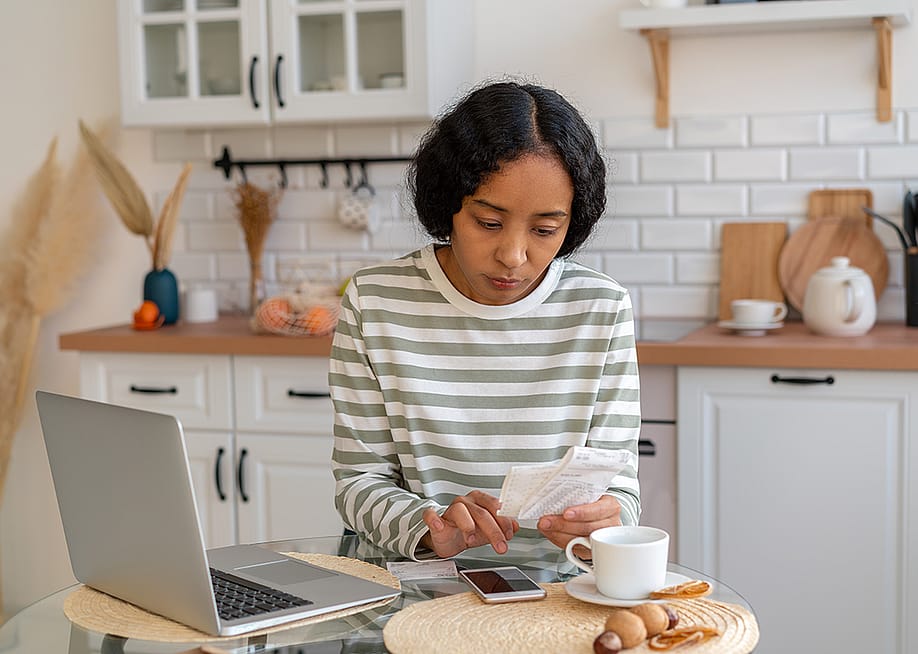 A young woman at home calculating expenses. — Nata Bene // Shutterstoc