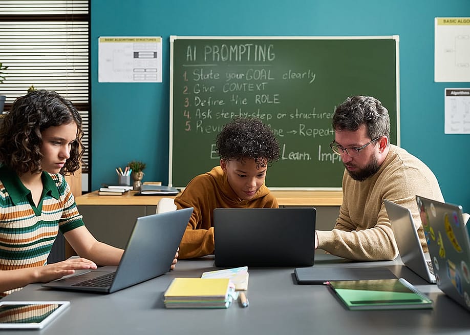 A male teacher guiding students in a classroom in using AI. — Pressmaster // Shutterstock