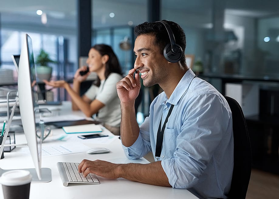 A happy male customer service representative in a call. — PeopleImages // Shutterstock