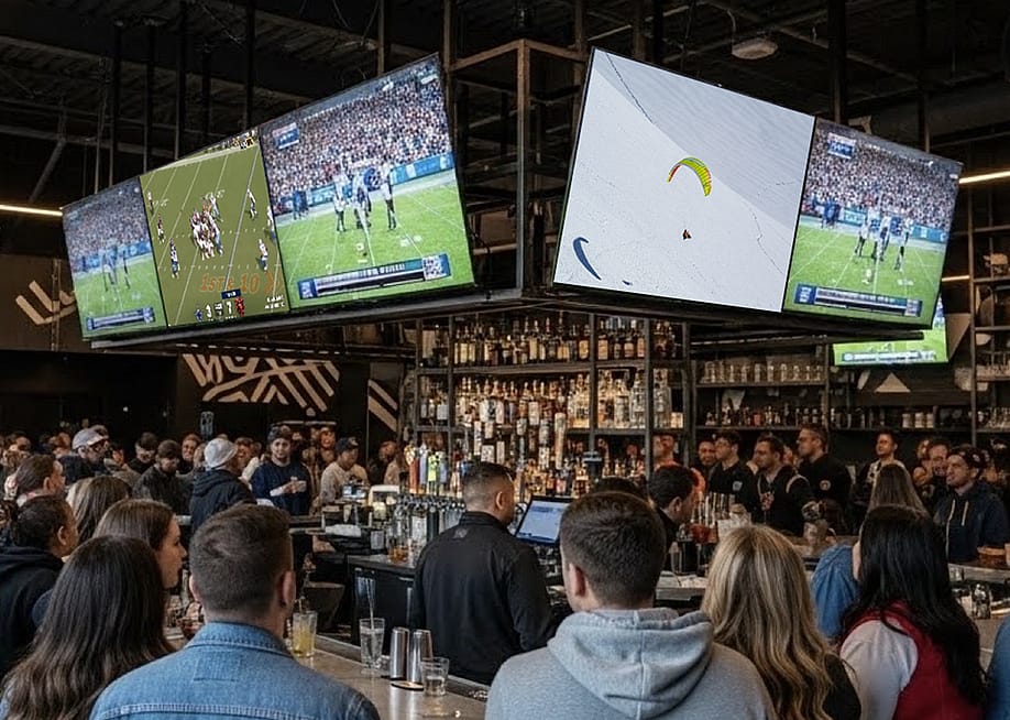 People surround a bar where multiple TVs stream a football match. — Atmosphere TV
