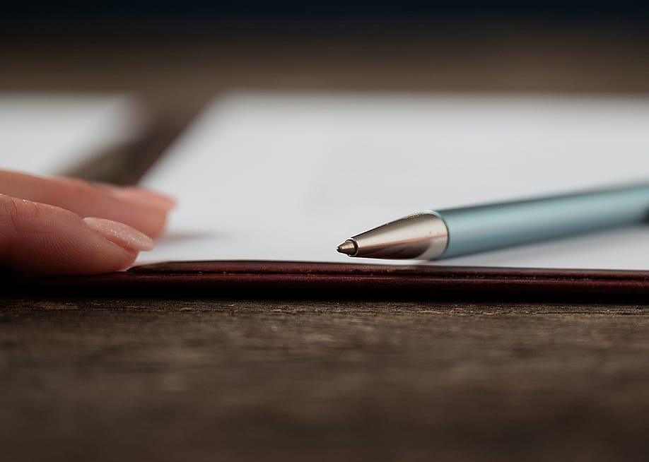 Low angle view of a hand and a pen lying on a document. — Gajus // Shutterstock