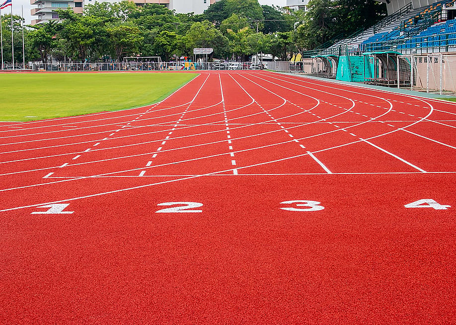 A red running track in an athletic stadium. — fotoglee // Shutterstock