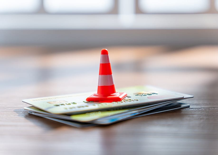 A traffic cone on a stack of credit cards. — izzuanroslan // Shutterstock