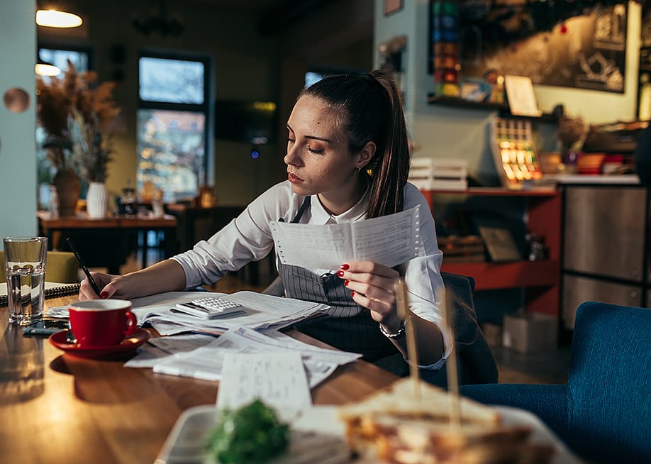 A female restaurant manager reviewing finance reports. — Dejan Dundjerski // Shutterstock