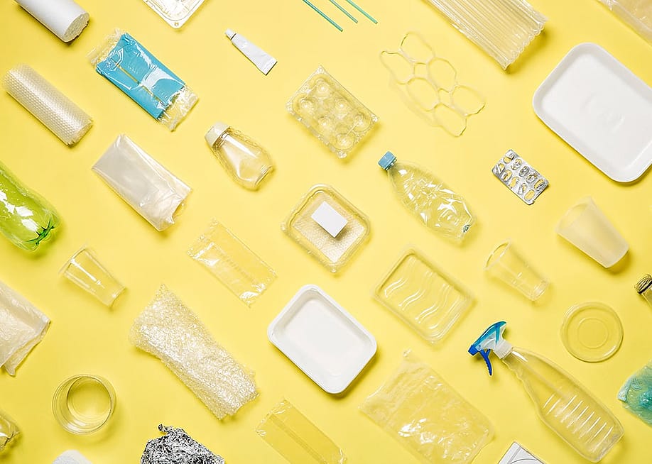 Different types of plastic packaging neatly arranged with a yellow background. — Almost Green Studio // Shutterstock