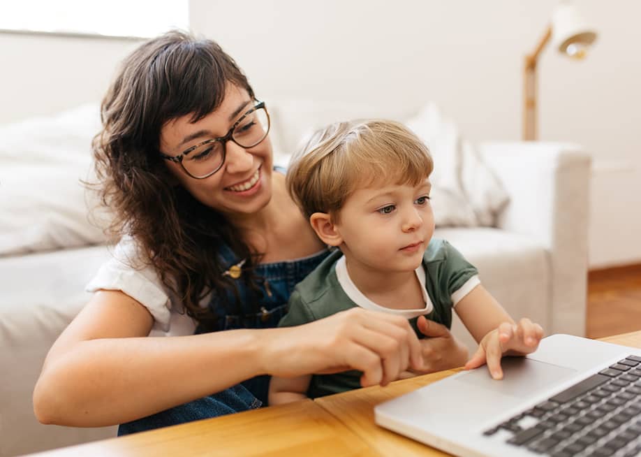 A mother and a son checking on a laptop in a living room. — JLco Julia Amaral // Shutterstock