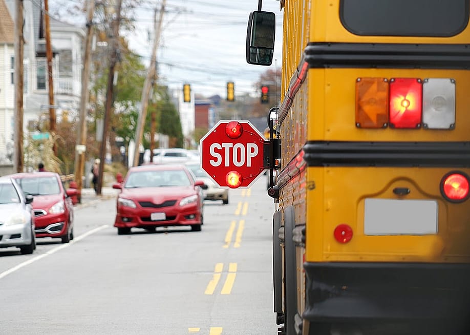 Rear view of a school bus with a 'stop' sign being held by its driver. — ND700 // Shutterstock