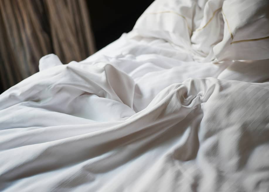 Soft white bedding on a cozy bed. — Towfiqu ahamed barbhuiya // Shutterstock