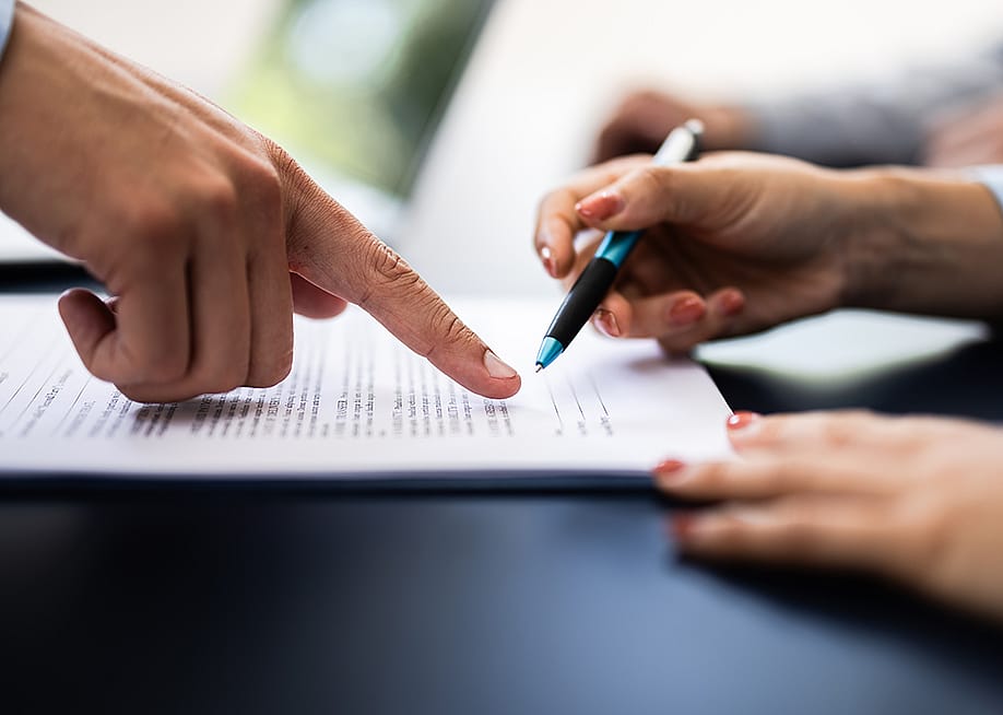 A pointing finger guiding the other person where to sign in a document. — Andrey_Popov // Shutterstock
