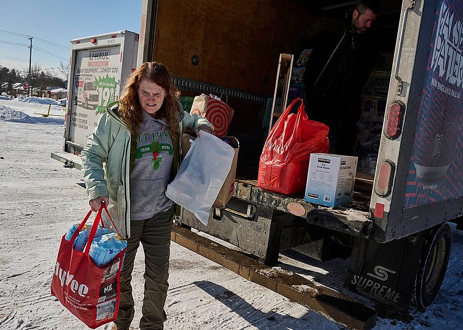 Leah Sheehy, a volunteer with Community Aid Network MN, moves donations from a truck parked in the snow in Minneapolis, Minnesota, on 2 February. — Bridget Bennett for The Economic Hardship Reporting Project and The Guardian