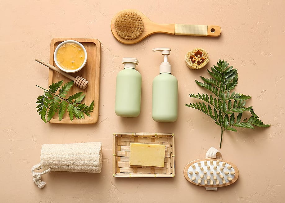 Soap, body scrub, brushes and bathroom essentials laid on a beige surface. — Pixel-Shot // Shutterstock