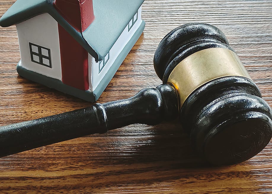 A miniature house and a gavel in a wooden surface. — Faizal Ramli // Shutterstock