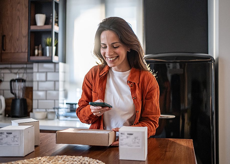 A woman scanning a package's QR code with a phone. — Migma__Agency // Shutterstock