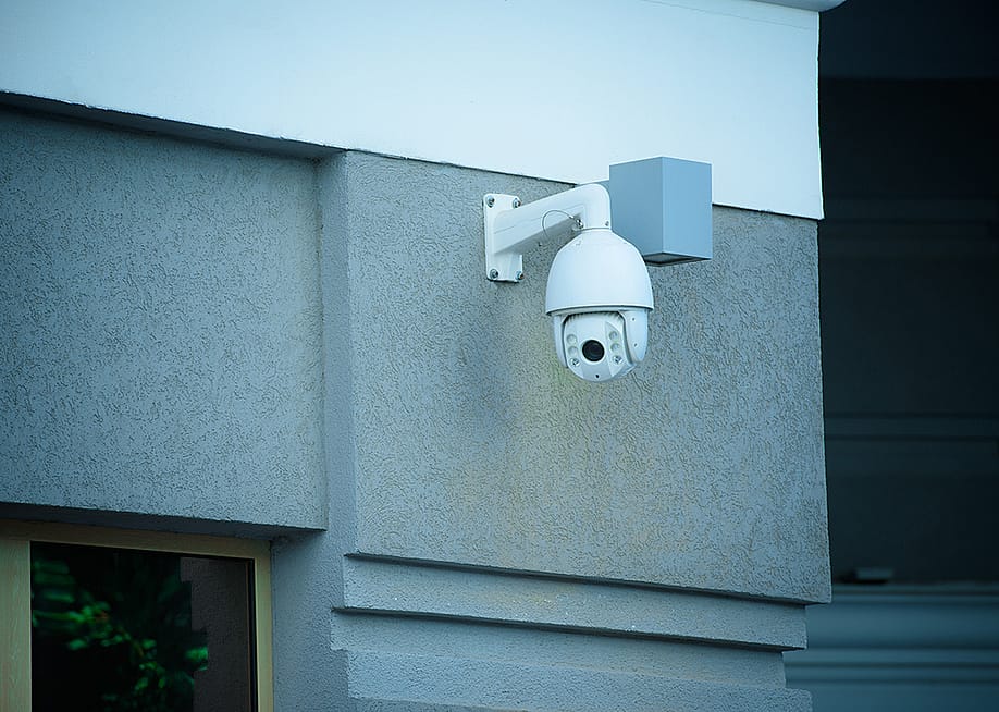A view of a security camera on the facade of a gray building. — LightField Studios // Shutterstock
