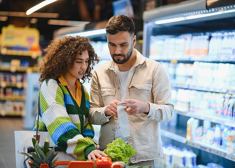 A young couple looking at their list while grocery shopping. — Hryshchyshen Serhii // Shutterstock