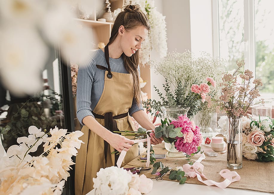 A female small business owner arranging flowers in her shop. — illustrissima // Shutterstock