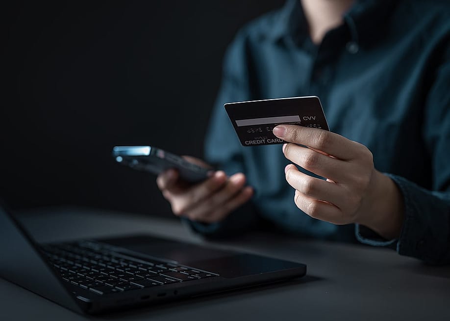 A person checking credit card details from a smartphone and laptop. — Garun .Prdt // Shutterstock