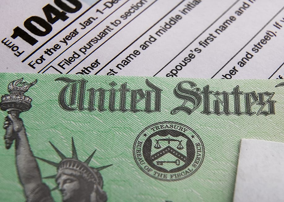 A U.S. tax refund check over a 1040 tax form. — Miro Vrlik Photography // Shutterstock