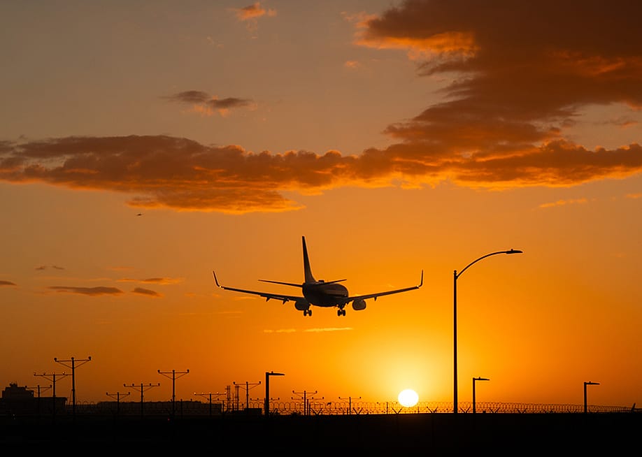 An airplane landing at Los Angeles International Airport during sunset in California, USA. — JohnNilsson // Shutterstock