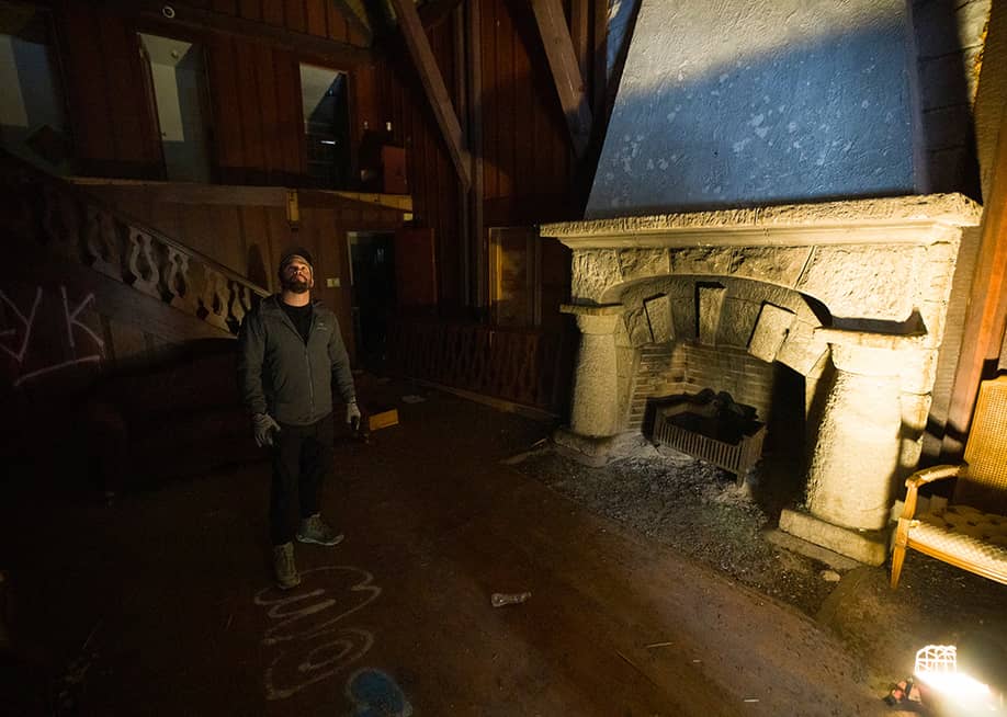 Cameron Jensen standing inside one of his newly acquired buildings in Logan Canyon in front a fireplace illuminated by a floor lamp. — Bethany Baker // The Salt Lake Tribune
