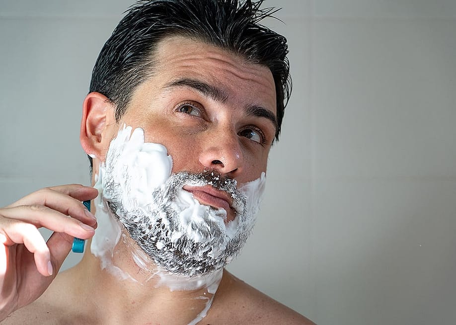 A young man shaving his beard. — nadia_costa // Shutterstock