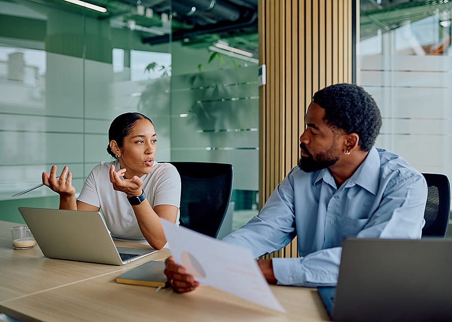 Two business colleagues engaged in discussion in a boardroom. — we.bond.creations // Shutterstock