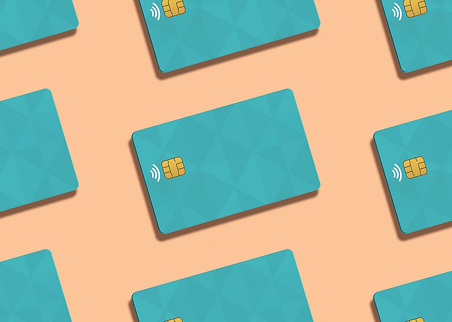 Teal credit cards against a peach background. — Elena Uve // Shutterstock