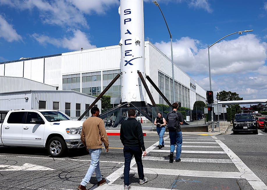 People walk outside a SpaceX facility in Hawthorne, California. — Photo by Mario Tama // Getty Images