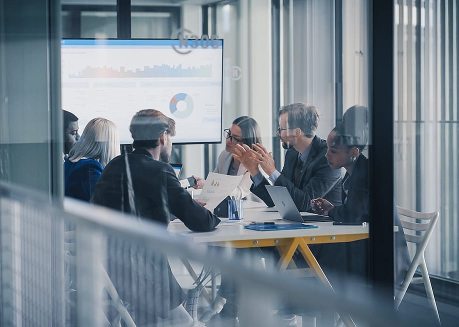 A business team inside a conference room discussing reports. — Gorodenkoff // Shutterstock