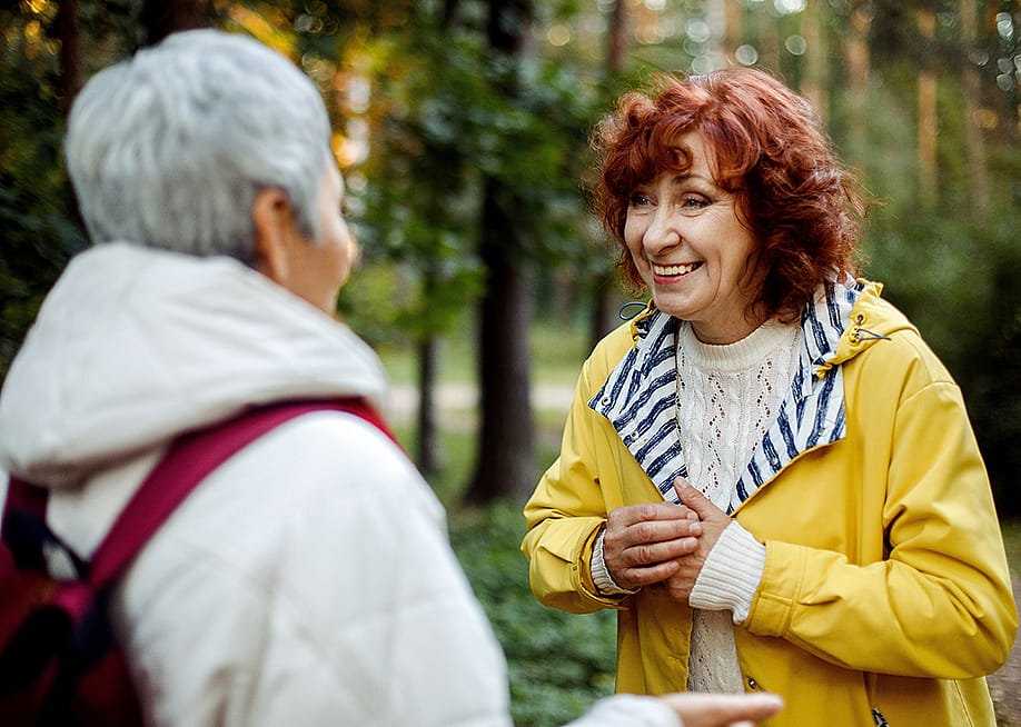 Two elderly female friends having a conversation out in the woods. — Raisa Kanareva // Shutterstock