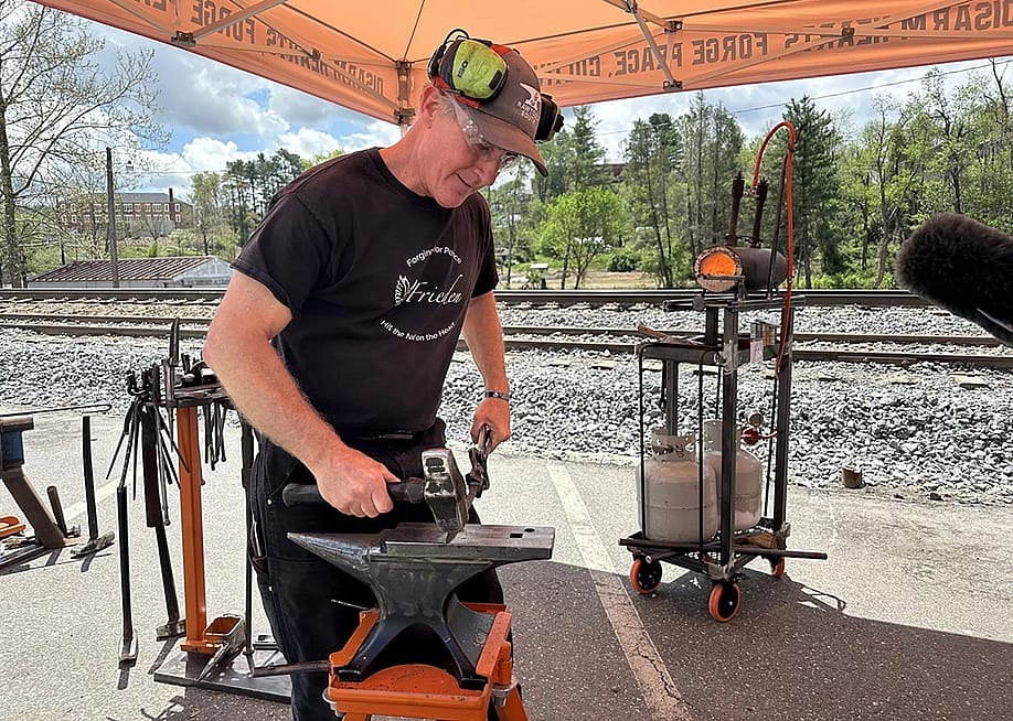 Scotty Utz, RAWtools South’s blacksmith, leads a demonstration at the 2025 Fire on the Mountain Festival in Spruce Pine, North Carolina. — Sarah Melotte // The Daily Yonder