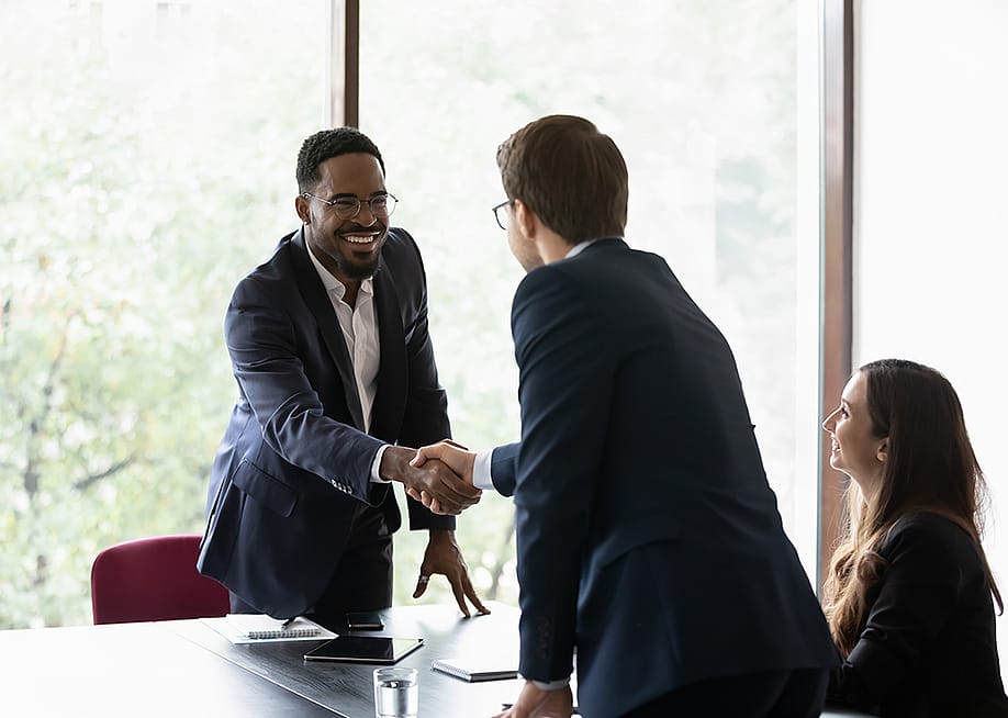 Business partners shaking hands after securing a sales deal in an office. — fizkes // Shutterstock
