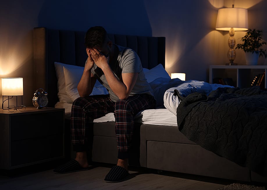 A man with his hands on his face after waking in the middle of the night. — New Africa // Shutterstock