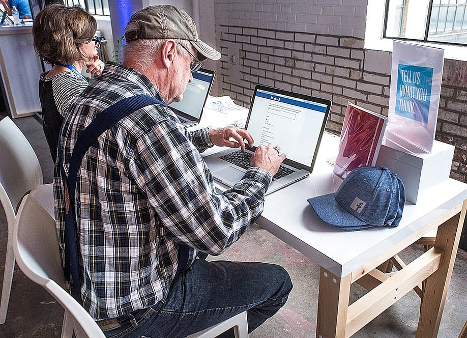 A senior man signing up for a Facebook account at a community boost event. — Jon Rehg // Shutterstock