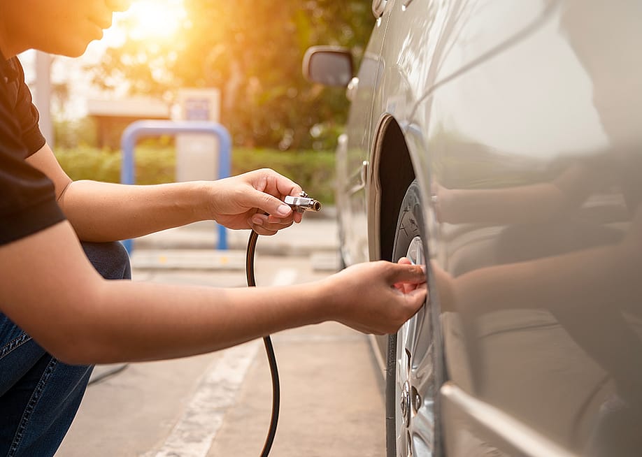 Man inflating car tires at a gas station. — Somchai // Shutterstock
