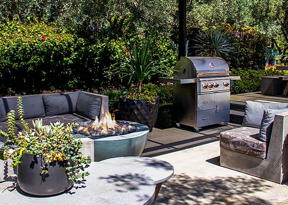 An outdoor entertainment space with gray sofas and a fire pit. — Wildfire Outdoor Living