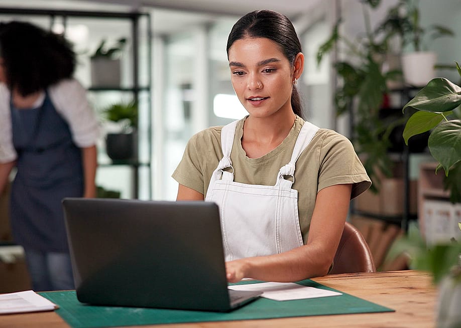 A female small flower business owner reviewing information on a laptop. — PeopleImages // Shutterstock