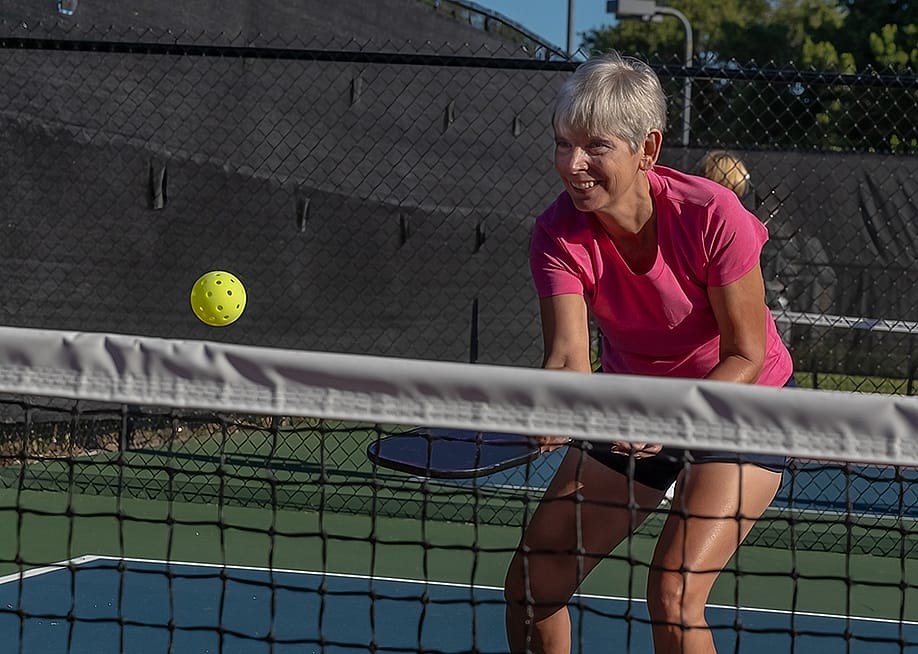An elderly person enjoying a good time while playing pickleball in a court. — jo Crebbin // Shutterstock