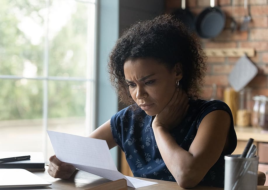 A frustrated young woman at home reading a letter with bad news. — fizkes // Shutterstock