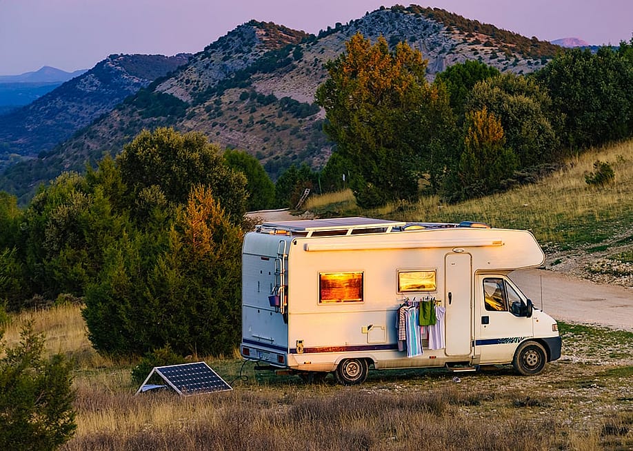 A motorhome recreational vehicle (RV) parked in a mountain for a holiday camping. — Voyagerix // Shutterstock