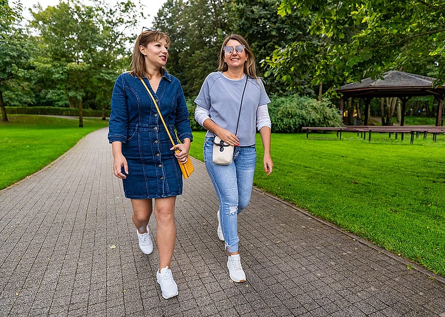 Two friends sharing stories while strolling in a city park. — Jacek Chabraszewski // Shutterstock