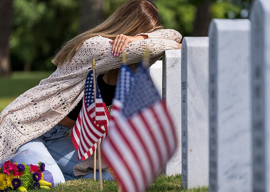 A young bridge grieving at a burial site of a family member in a military cemetery. — Grindstone Media // Shutterstock