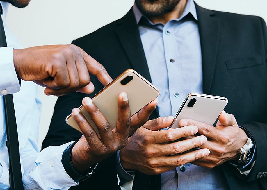 A business person showing an online post from his smartphone to a colleague. — Rawpixel.com // Shutterstock