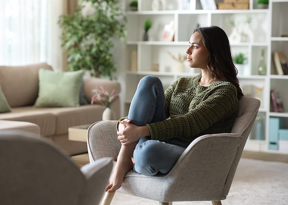 A woman sitting at home pensively looking out the window. — Antonio Guillem // Shutterstock