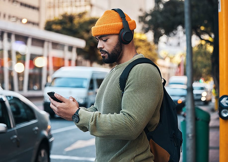 Man listening to music outdoors while about to cross a street. — PeopleImages // Shutterstock