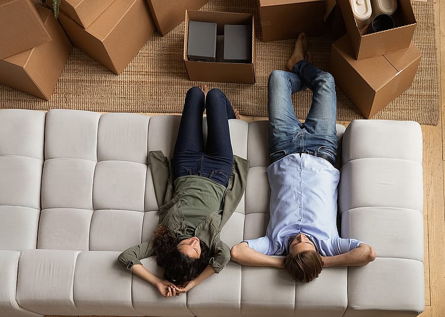 Overhead of a young couple taking a break on the sofa after moving to a new home. — fizkes // Shutterstock