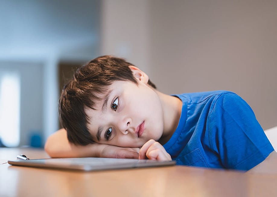 A bored young child staring at a tablet. — Ann in the uk // Shutterstock