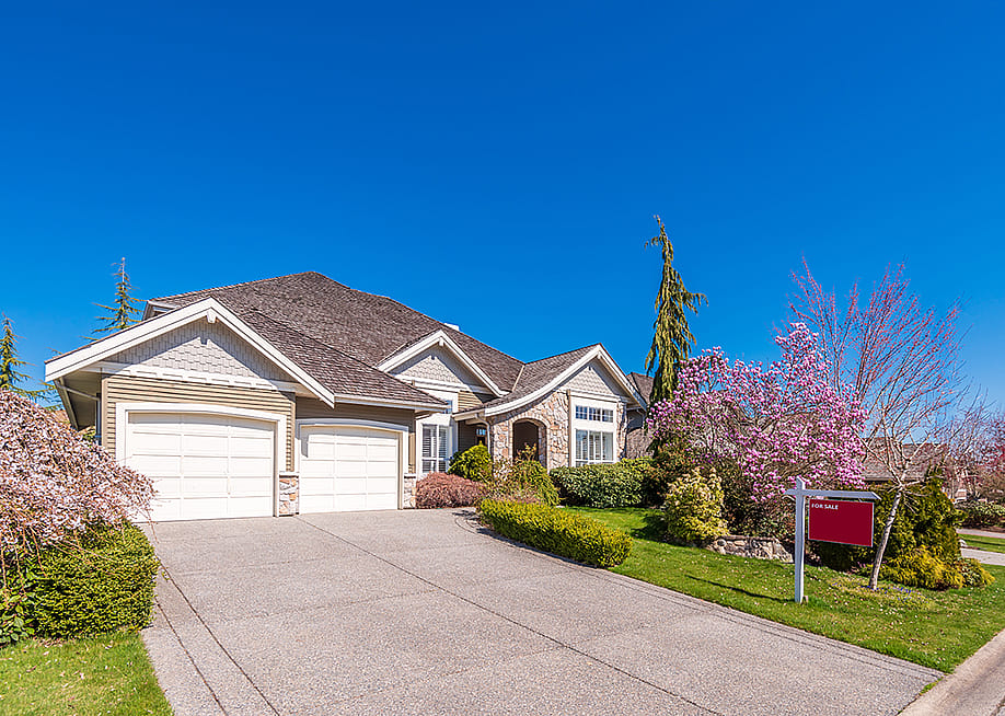 A multi-car garage residential property with a for sale sign. — karamysh // Shutterstock